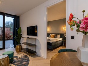 A modern hotel room with a bed, a TV, a small table, and a large window. - RustUit by Interhome (Koudekerke)