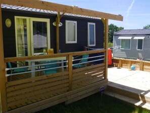 A wooden deck with a railing, a table, and chairs. - Mobile home for 4 people with terrace (Martiel)