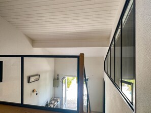 Ein Zimmer mit schrägen Wänden, einem großen Fenster und einer Tür, die nach draußen führt.