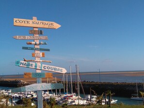 A directional signpost with multiple arrows pointing to various destinations, including 'Cote Sauvage' and 'La Palmyre.'