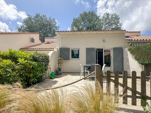 Ein Haus mit Terrasse, Holzzaun und Garten.