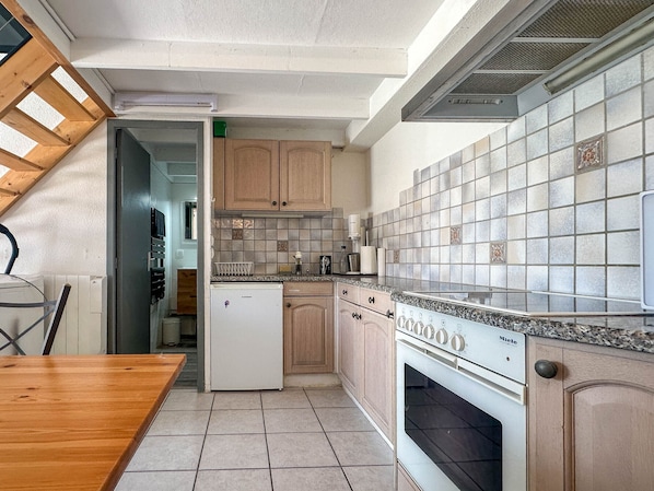A kitchen with wooden cabinets, a tiled backsplash, a built-in oven, and a dining area with a wooden table.