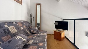 Een moderne woonkamer met een bank, een flatscreen televisie en een houten bijzettafeltje.