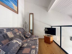 Ein modernes Wohnzimmer mit einer Couch, einem Flachbildfernseher und einem Holztisch.