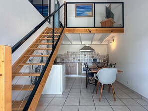 Eine moderne Küche mit Essbereich, eine Treppe mit Holzgeländern und Meerblick durch ein Fenster.