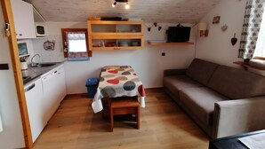 Ein kompakter Wohnbereich mit Küchenzeile, Esstisch, Sofa und Fernseher.