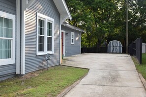 A residential property with a grey siding exterior, a concrete driveway, and a fenced backyard. - Northport Nest- Newly Renovated Modern Farmhouse (Northport)