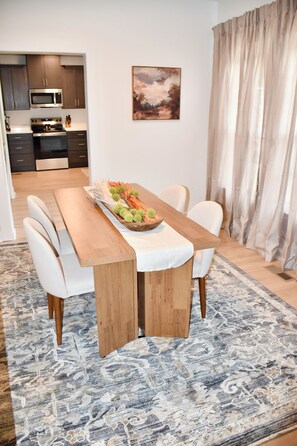 A dining area with a wooden table, white chairs, and a decorative centerpiece. - Northport Nest- Newly Renovated Modern Farmhouse (Northport)