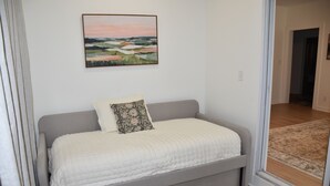 A bedroom with a bed, a pillow, a painting on the wall, and a view through a glass door. - Northport Nest- Newly Renovated Modern Farmhouse (Northport)