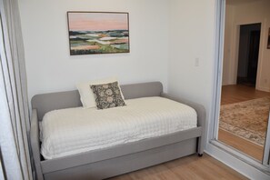 A bedroom with a bed, a pillow, a painting on the wall, and a view through a glass door. - Northport Nest- Newly Renovated Modern Farmhouse (Northport)
