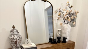 A wooden console table with a mirror, decorative items, and a vase with flowers. - Northport Nest- Newly Renovated Modern Farmhouse (Northport)