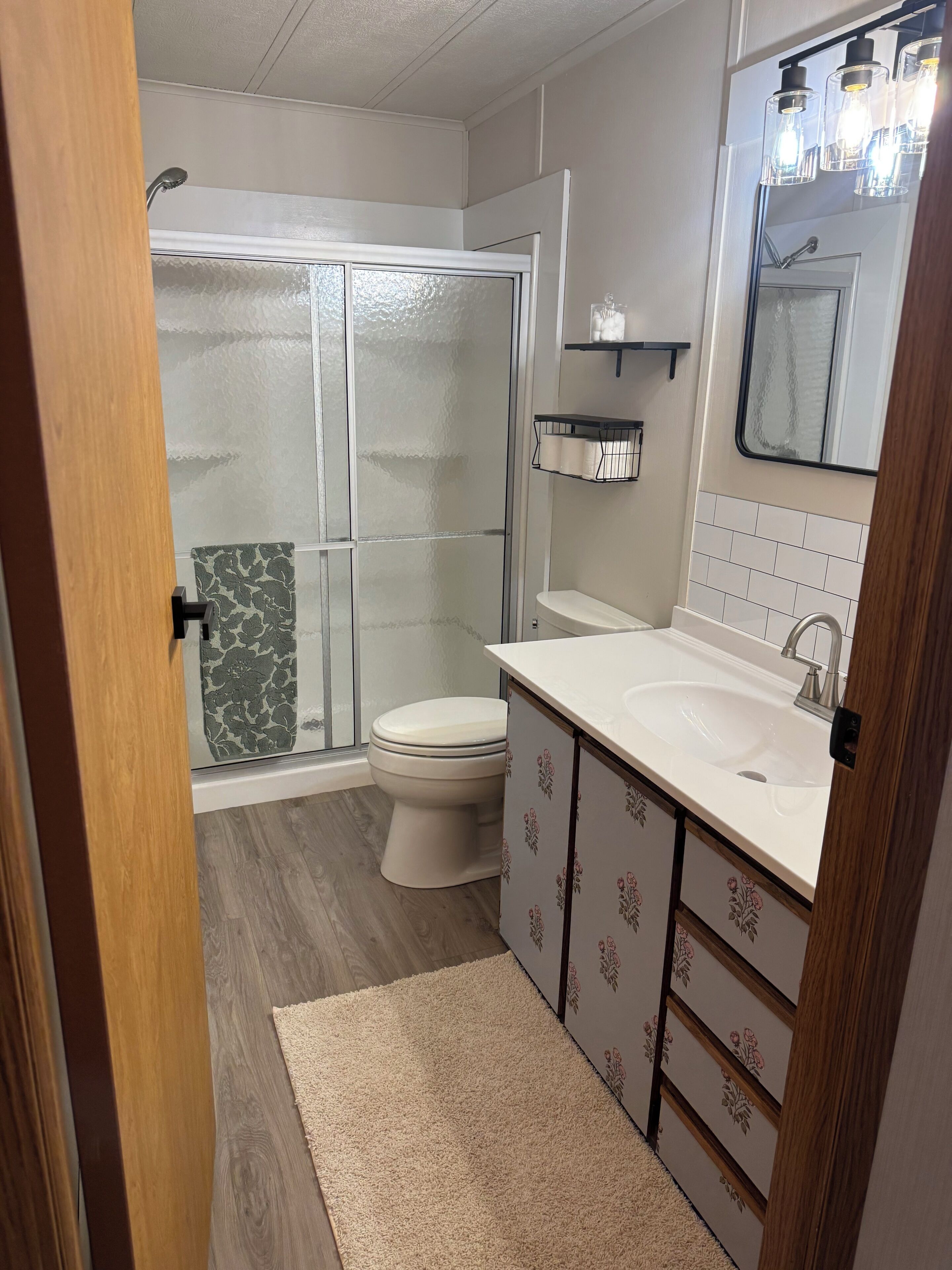 A bathroom with a shower, toilet, sink, and cabinet.