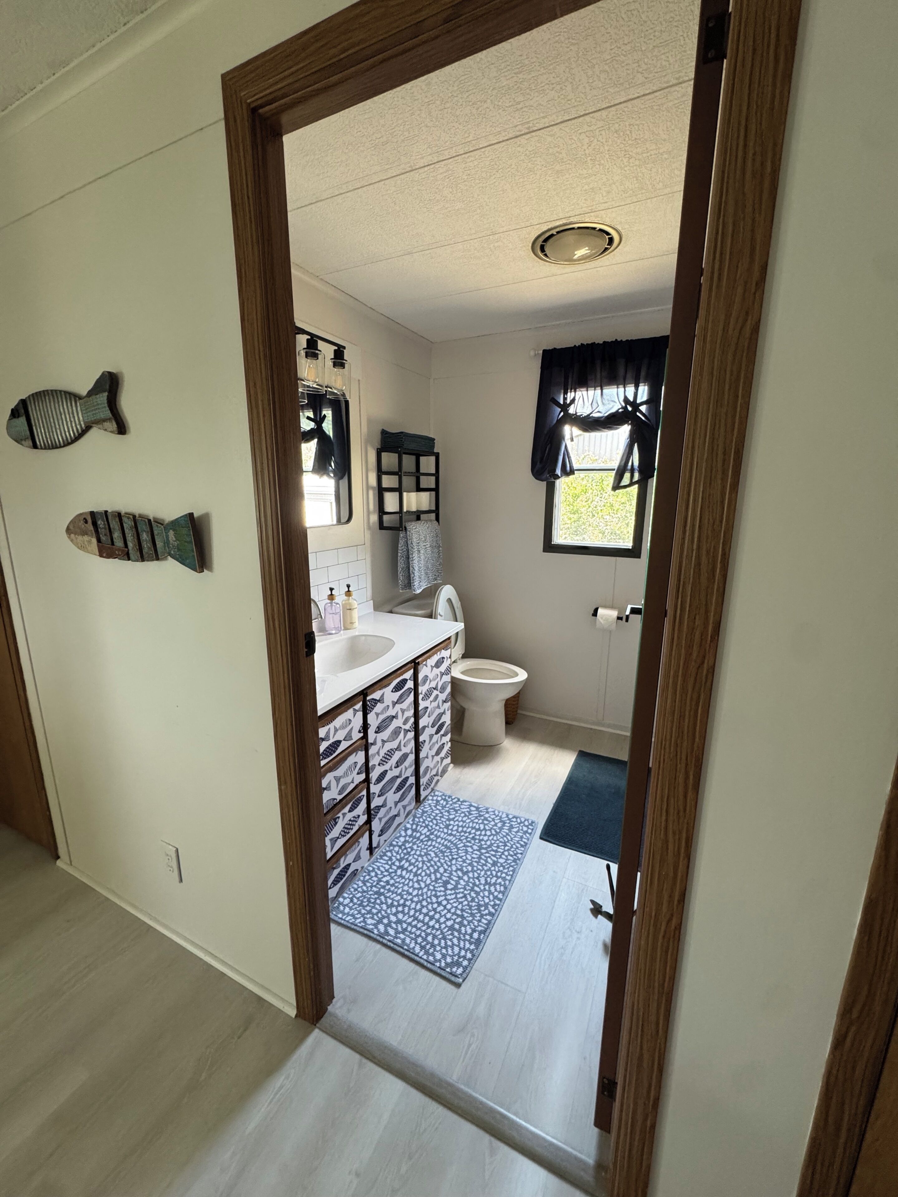A bathroom with a toilet, sink, and window with curtains.