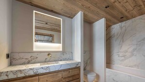 A bathroom with a wooden ceiling, marble countertop, and a modern sink. - Ski-in/ski-out apartment at Rond-Point des Pistes (Méribel)