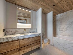 Ein Badezimmer mit Holzboden, Marmorplatte und einem modernen Waschbecken.