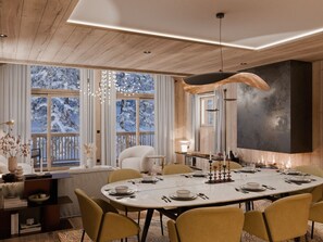 Ein moderner Essbereich mit einem großen Tisch, gedeckt für sechs Personen, umgeben von Stühlen und einem großen Fenster mit Blick auf schneebedeckte Bäume.