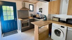 Ett kompakt kök med en inbyggd ugn, en mikrovågsugn, en kaffebryggare och en tvättmaskin.