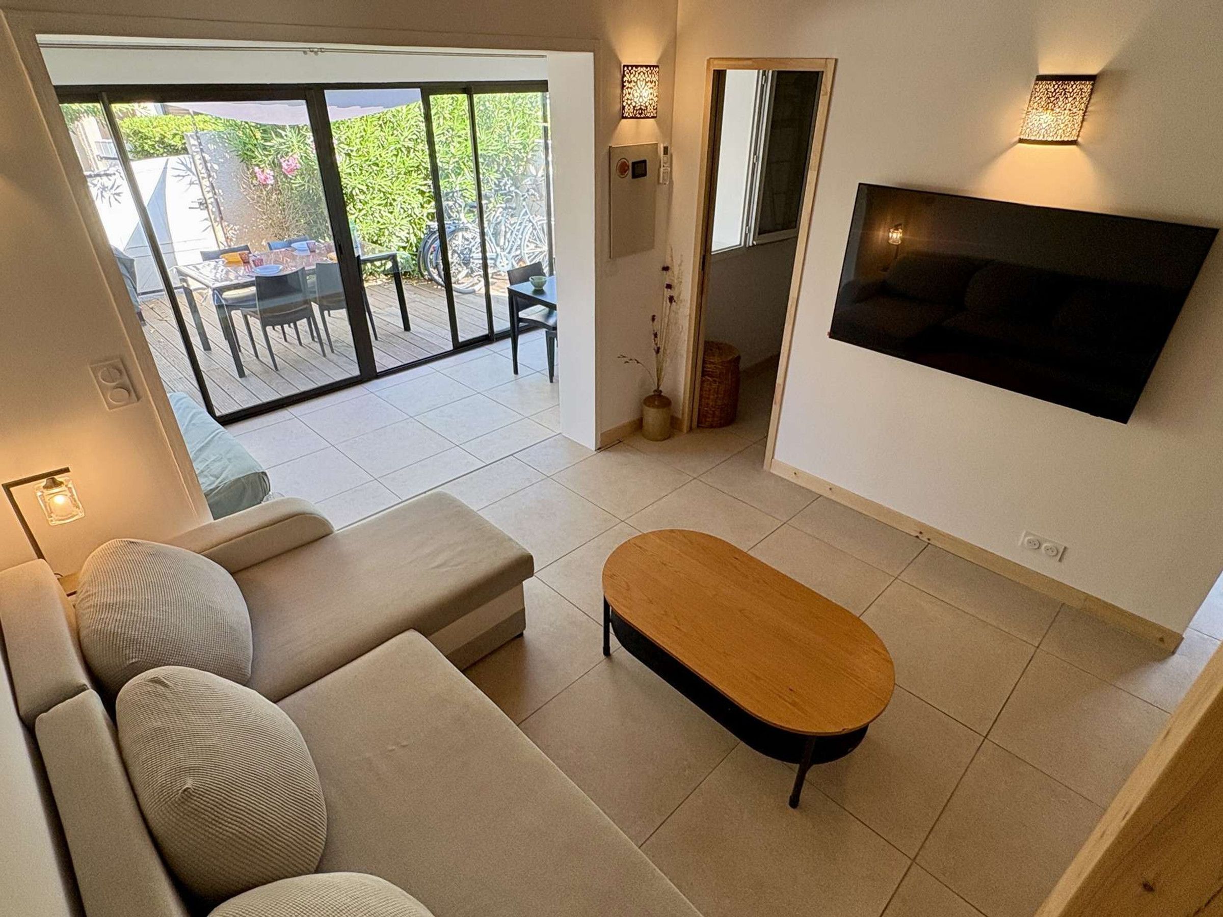 A modern living room with a sofa, a wooden coffee table, and a TV mounted on the wall.