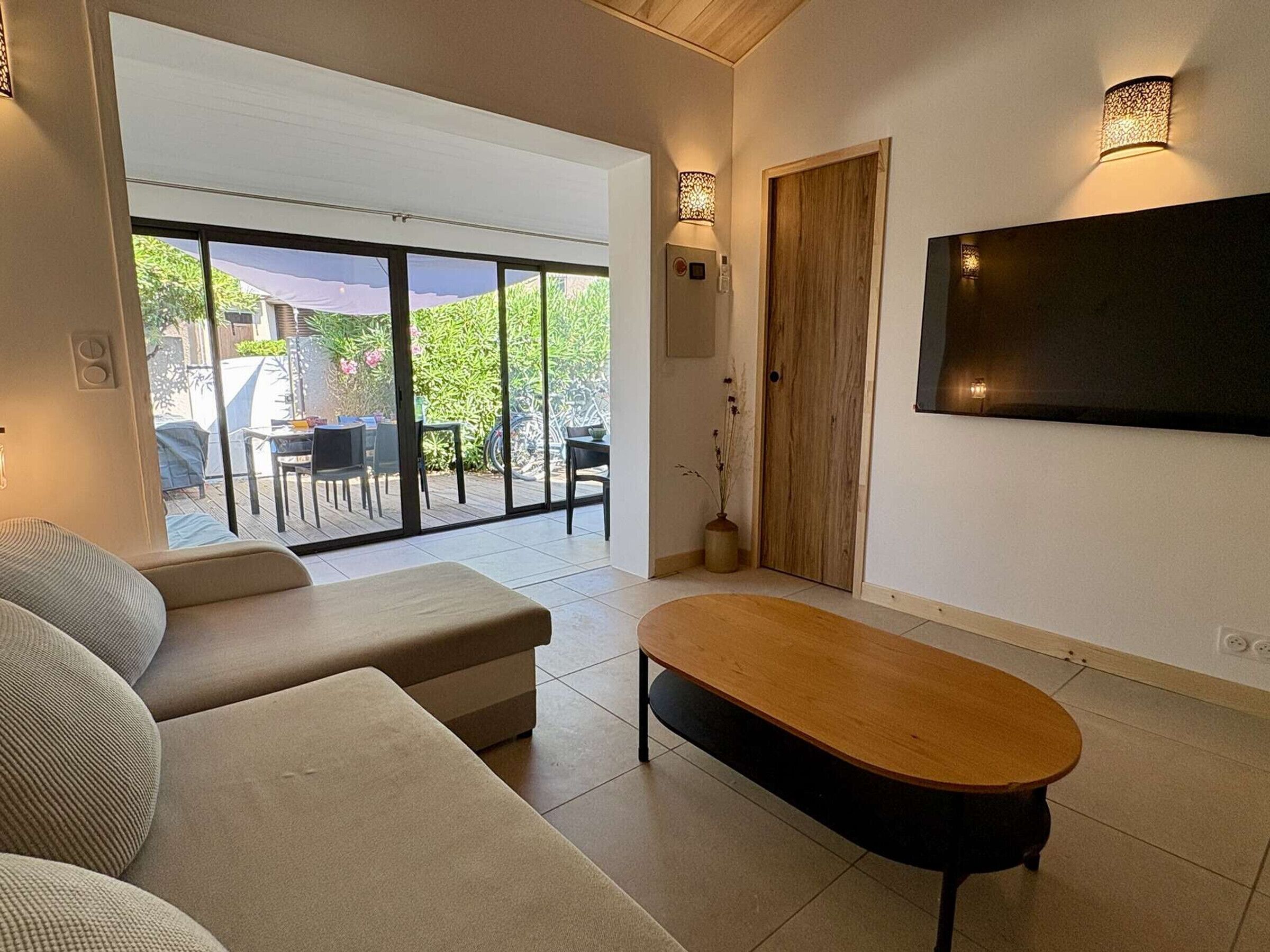 A modern living room with a sofa, a wooden coffee table, and a TV mounted on the wall.