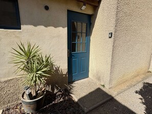 Ein Gebäude mit blauer Tür, einem Blumentopf und einer strukturierten Wand.