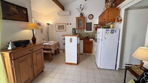A compact kitchen with wooden cabinets, a central island, and a white refrigerator. - Apartment with pool, parking - 6 guests (Saint-Aygulf)