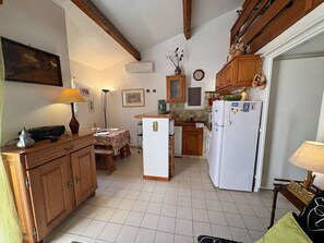 A compact kitchen with wooden cabinets, a central island, and a white refrigerator. - Apartment with pool, parking - 6 guests (Saint-Aygulf)