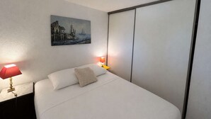 A hotel room with a bed, a painting on the wall, and two bedside lamps. - Apartment with pool, parking - 6 guests (Saint-Aygulf)