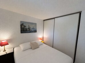 A hotel room with a bed, a painting on the wall, and two bedside lamps. - Apartment with pool, parking - 6 guests (Saint-Aygulf)
