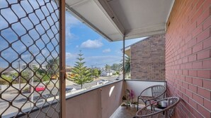 Uma varanda com vista para a rua, um muro de tijolos e duas cadeiras de vime.