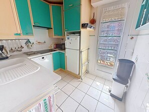 A kitchen with teal cabinets, a white refrigerator, and a tiled backsplash. - Apartment sea view - 4 guests (Cabourg)
