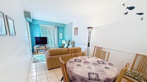 A living room with a sofa, TV, and a dining table with chairs. - Apartment sea view - 4 guests (Cabourg)