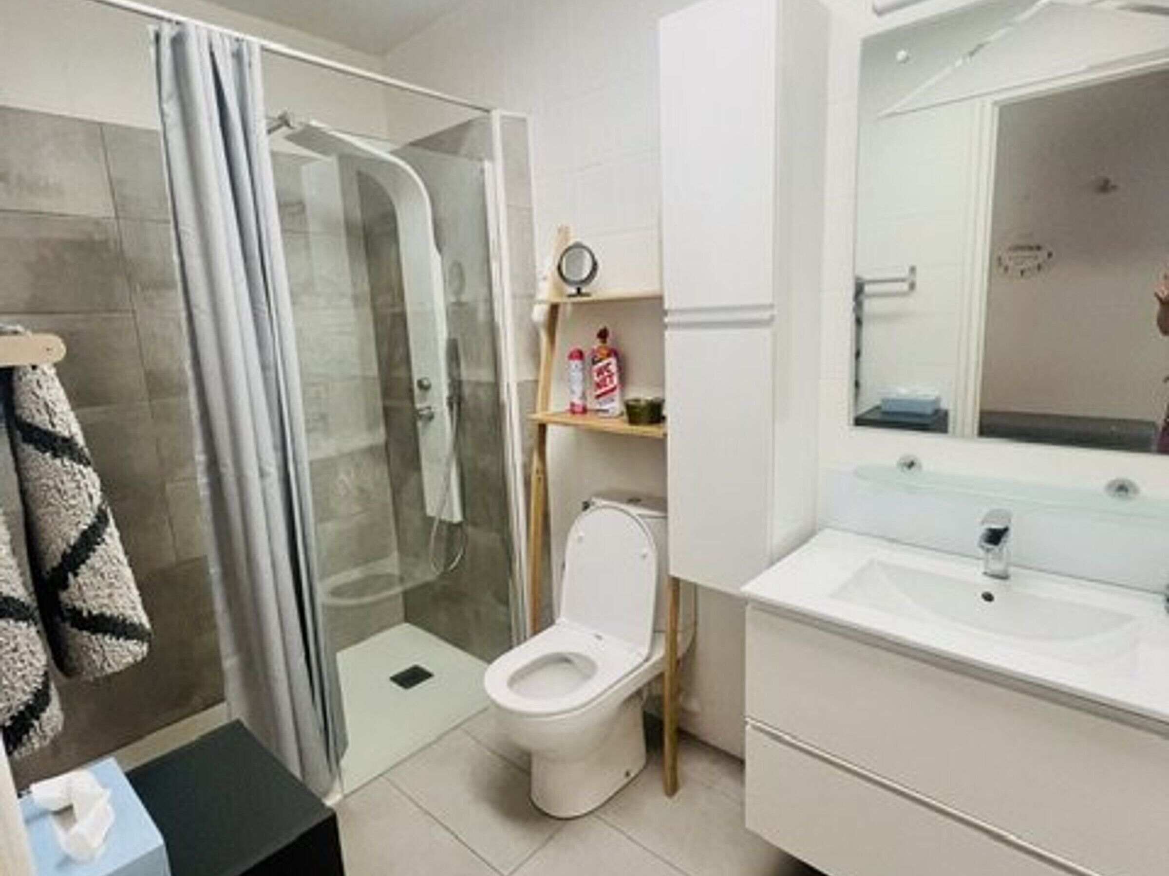 A bathroom with a glass-enclosed shower, a toilet, a sink, and a mirror.