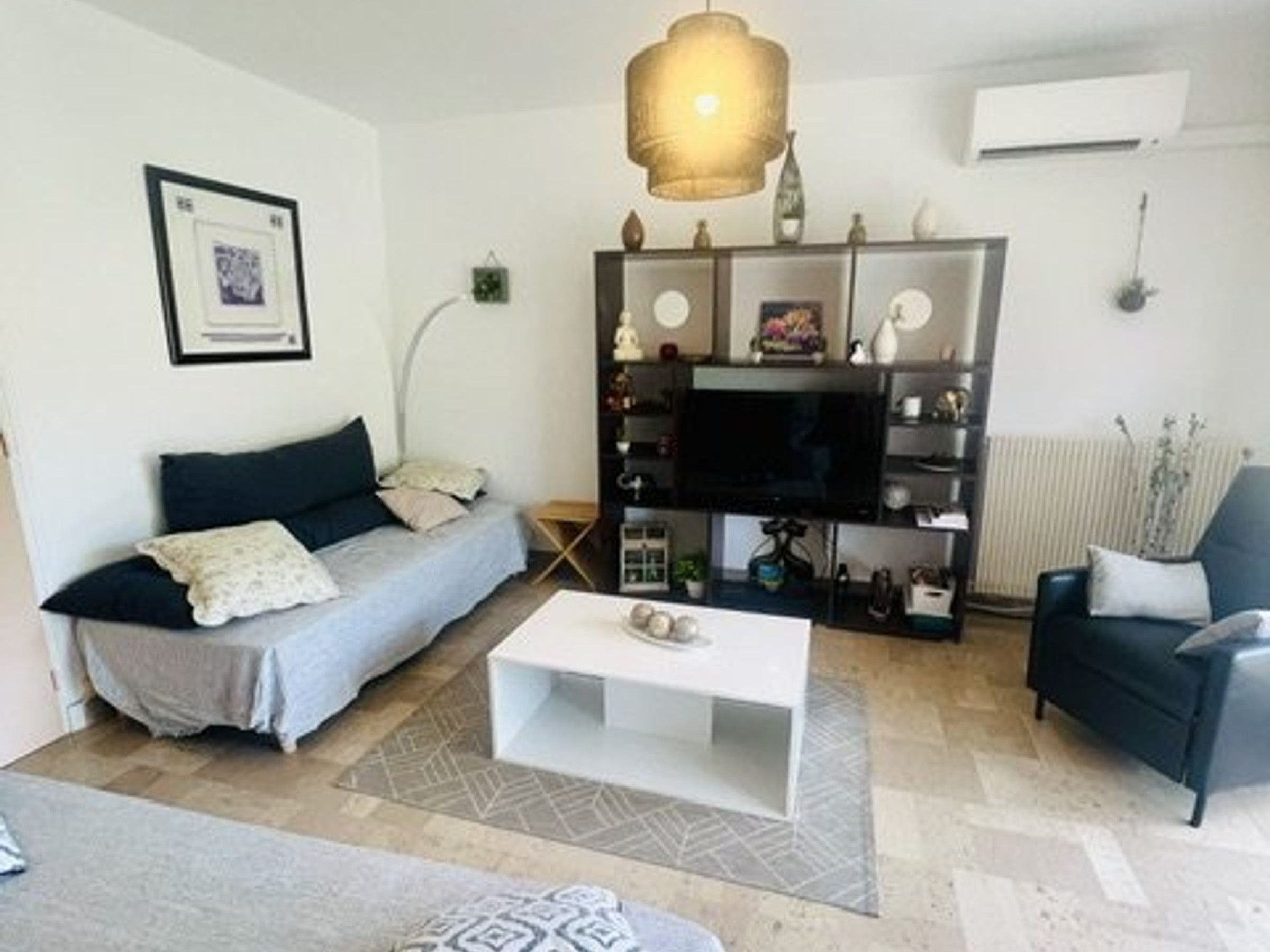 Un salon comprenant un canapé, une table basse, un meuble pour la télévision et un fauteuil.