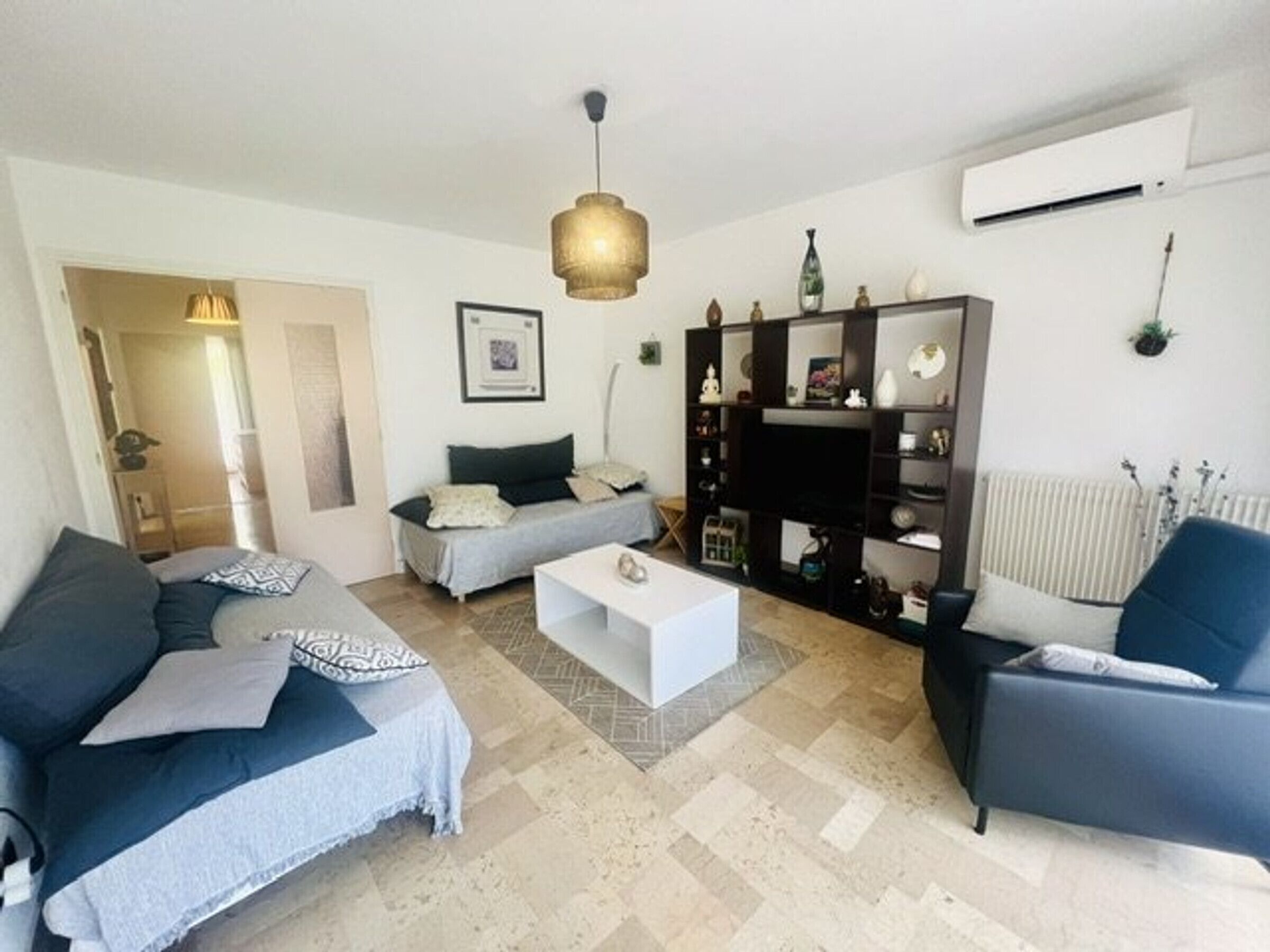 A living room with a sofa, a coffee table, a TV stand, and a radiator.