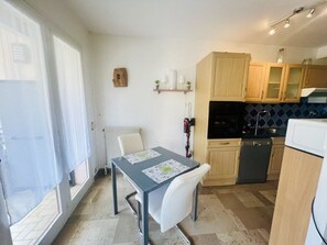 A compact kitchen with a dining table, chairs, and basic appliances. - F2 Apartment, pets allowed - 2 guests (AMELIE LES BAINS)