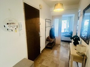 Ein Flur mit Tür, einer Sitzbank, einer Wandleuchte und einem Spiegel.