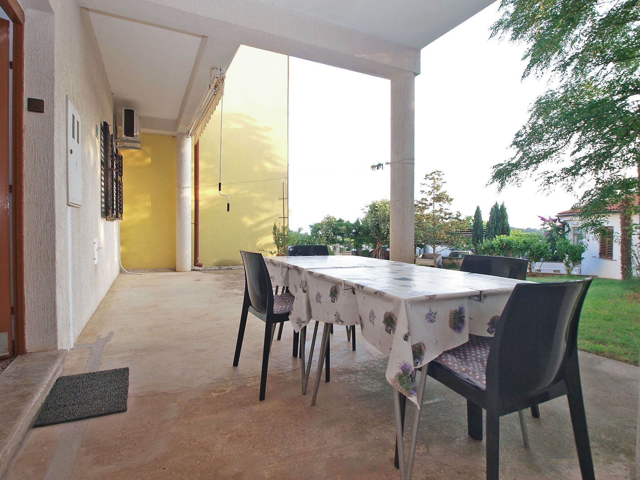 An outdoor patio with a table and chairs, a yellow wall, and a view of the surrounding area.