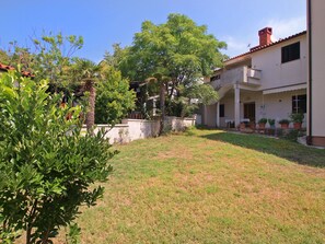 A residential property with a grassy yard, a tree, and a two-story building with a balcony. - Apartment 1707 by Interhome (Pula/Banjole)