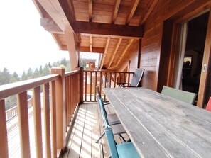 A wooden deck with a table and chairs, a railing, and a view of the outdoors. - Spacious apartment with parking - 6 guests (Crest-Voland)