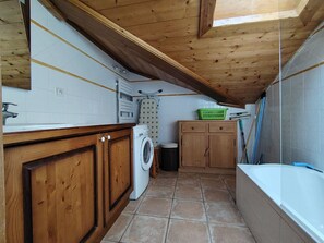 A compact kitchen with wooden cabinets, a washing machine, a drying rack, and a tiled floor. - Spacious apartment with parking - 6 guests (Crest-Voland)