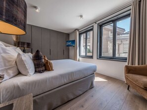 A bedroom with a large bed, a TV mounted on the wall, and a window with curtains. - Chic apartment, pets welcome - 8 guests, near slopes (Courchevel 1550)