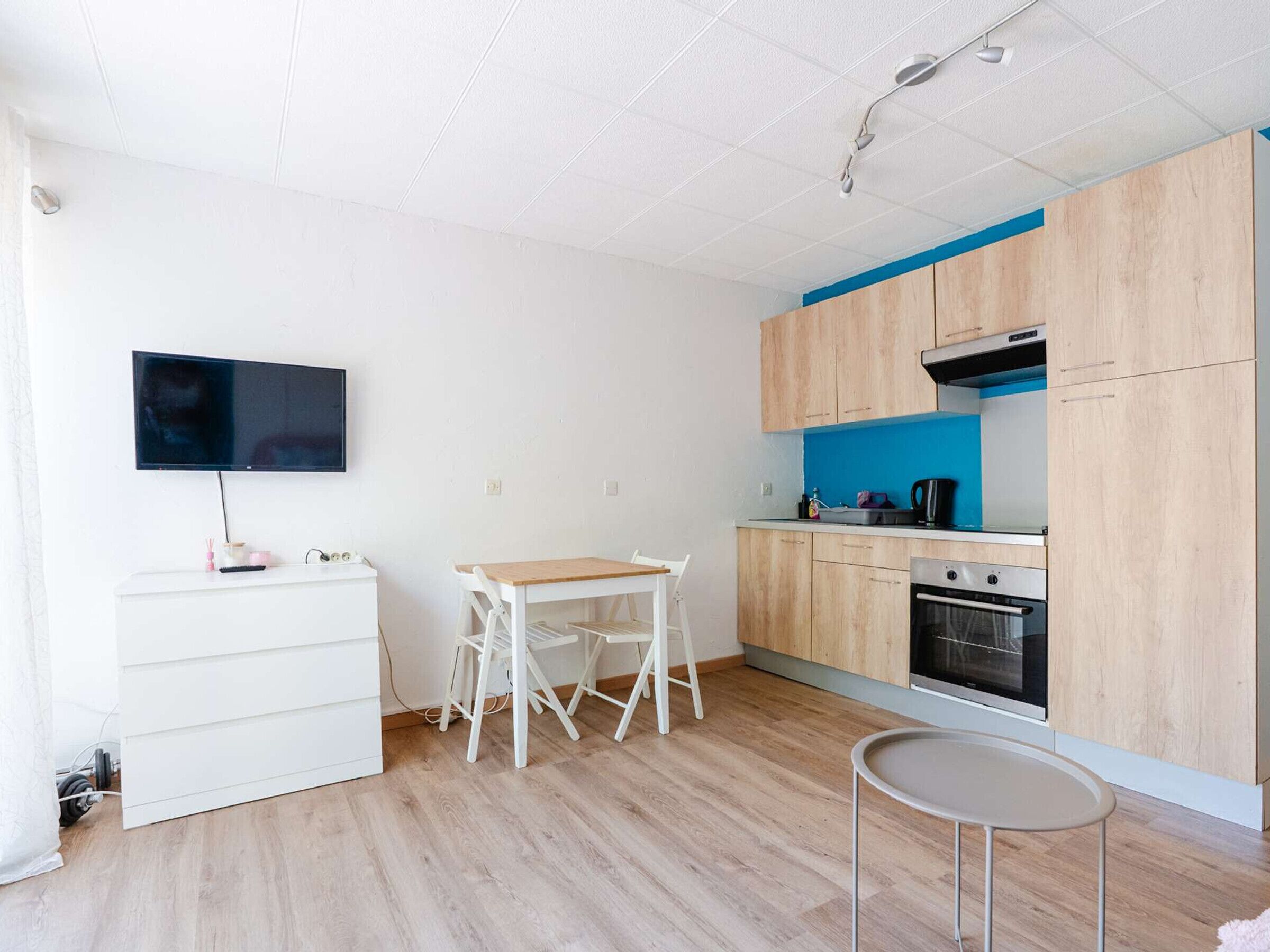 Una cocina moderna con armarios de madera, horno integrado y televisor de pantalla plana montado en la pared.