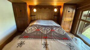 Een gezellig houten kamer met een bed, twee wandlampen en een raam.