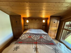 Ein gemütliches Holzhütten-Zimmer mit einem Bett, zwei Wandleuchten und einem Fenster.