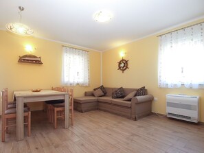 Ein Wohnzimmer mit Esstisch, einer Couch und einer wandmontierten Klimaanlage.