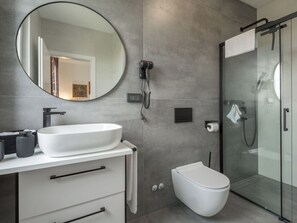 A modern bathroom with a large oval sink, a toilet, a glass shower enclosure, and a round mirror. - House 2258 by Interhome (Pula)
