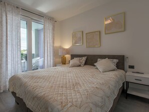 Un dormitorio con una cama grande, una mesita de noche, una lámpara y vistas al exterior.
