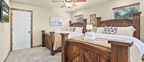 A bedroom with a wooden bed, a ceiling fan, a door, and a window with blinds.