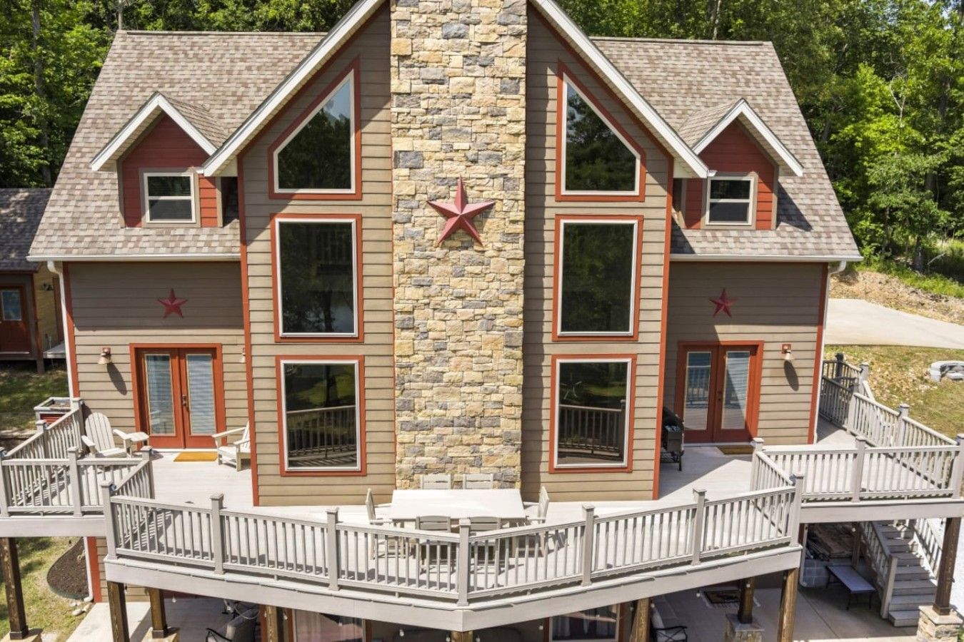 A two-story house with a stone facade, multiple windows, and a deck with railings.