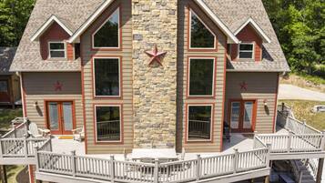 A two-story house with a stone facade, multiple windows, and a deck with railings.